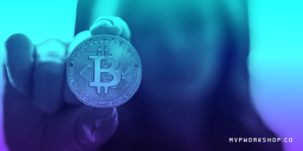 Blurred girl holding a coin with Bitcoin sign with blue filter